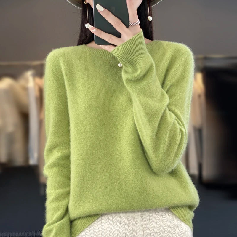Person wearing a green sweater taking a mirror selfie.