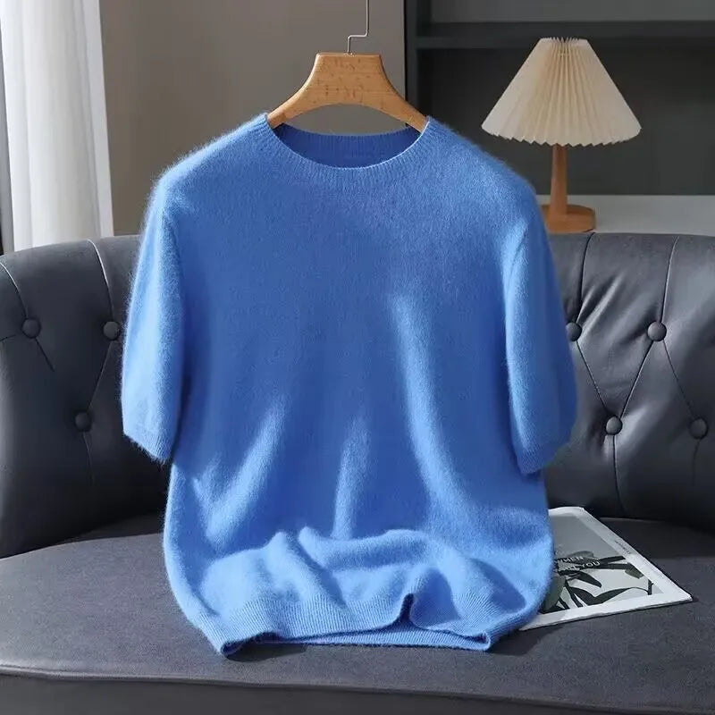 Blue sweater on a hanger against a gray sofa with a lamp in the background