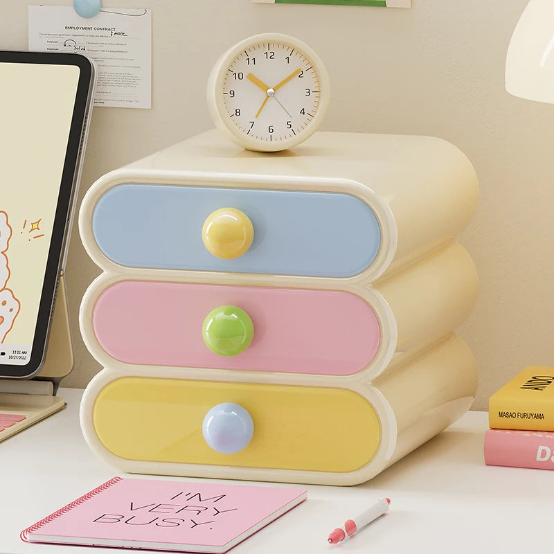 Pastel-colored three-drawer organizer with colorful knobs on a desk.