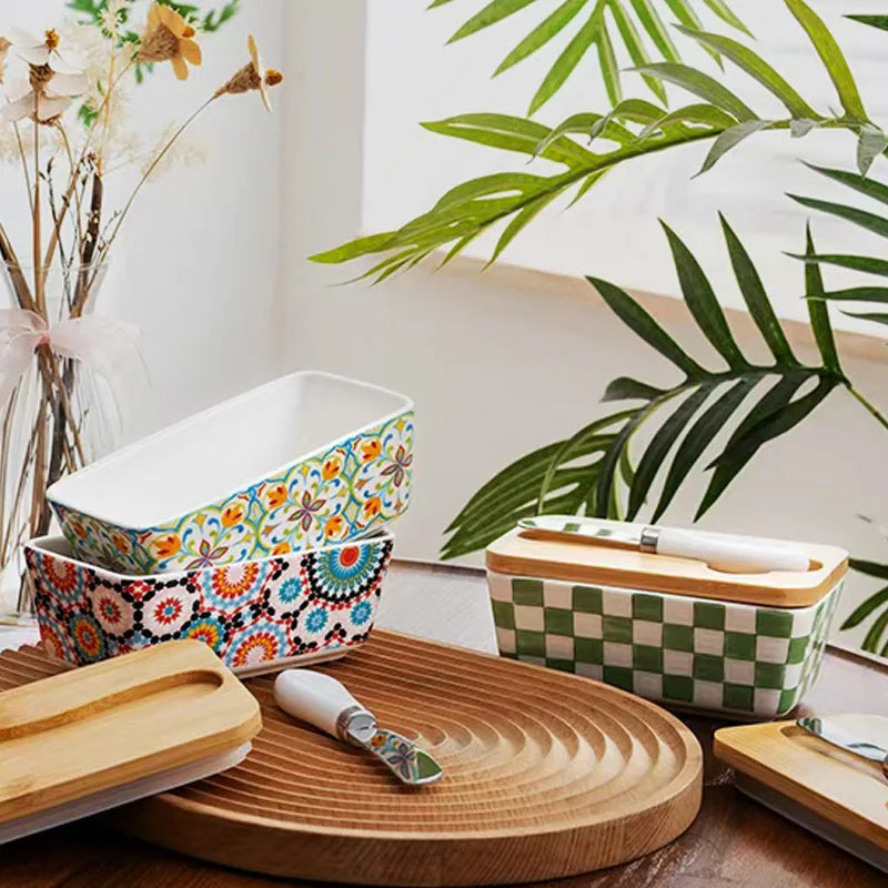 Decorative ceramic containers with floral patterns on a wooden surface with plants in the background
