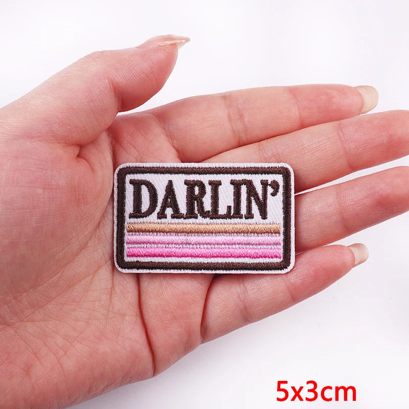 Hand holding a patch with 'Darlin'' text on a white background