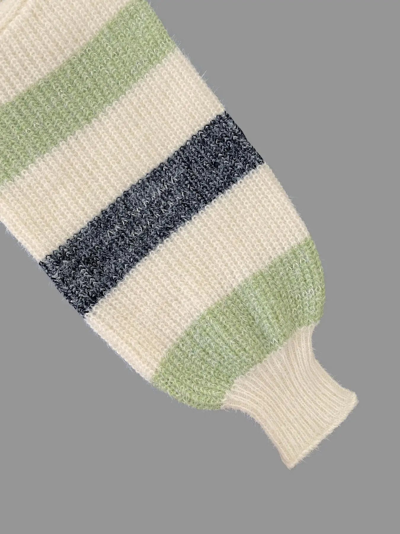 Close-up of a knitted item with green and blue stripes on a gray background