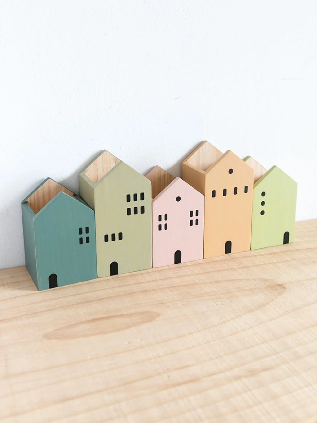 Set of colorful wooden house-shaped containers on a wooden surface with a white background