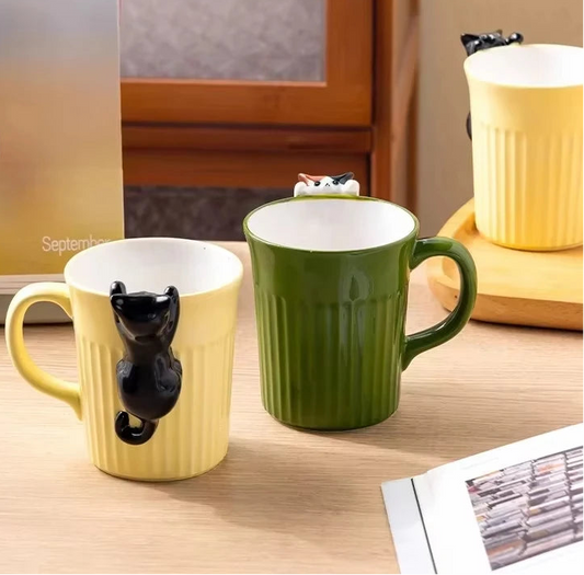 Green and yellow ceramic cat mugs with a 3D cat climbing over the rim.