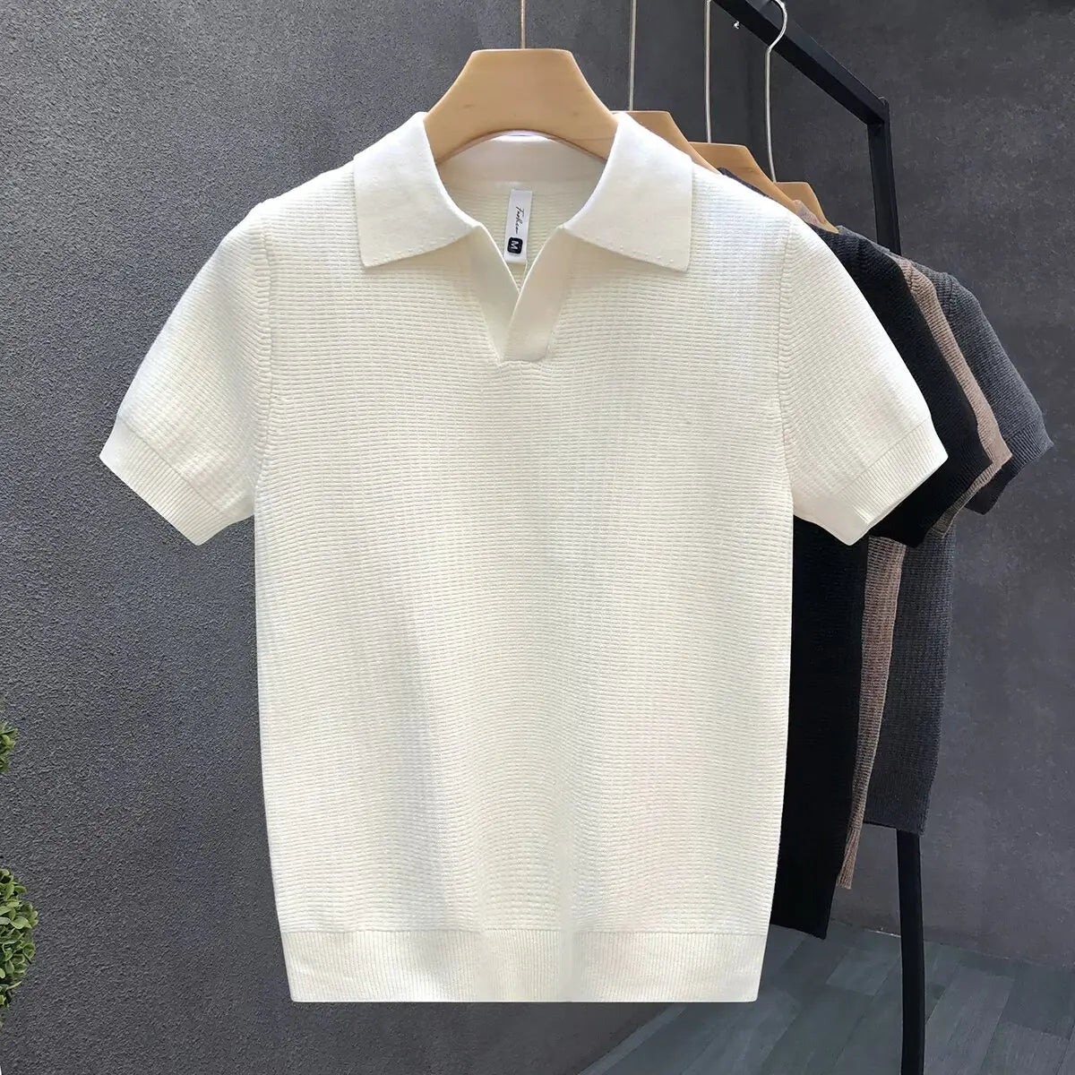 White textured polo shirt on a hanger against a gray background