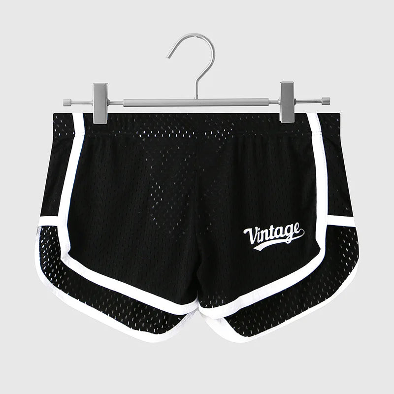 Black mesh shorts with white accents on a hanger against a light gray background