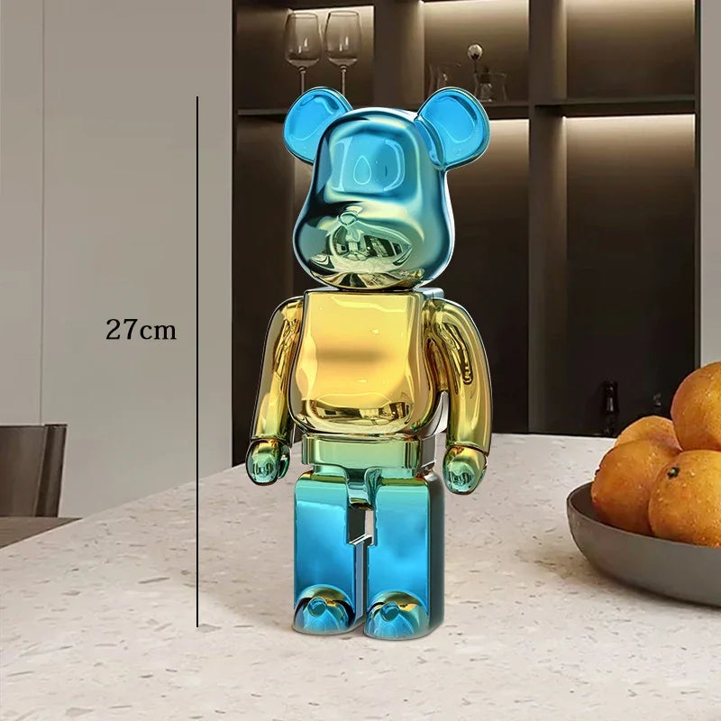 Multicolored bear-shaped figure on a table with a bowl of oranges in the background