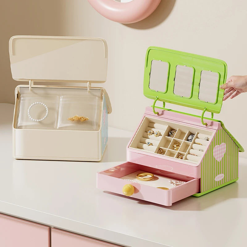 Two jewelry boxes, one open beige and one pink with green lid, on a light surface.