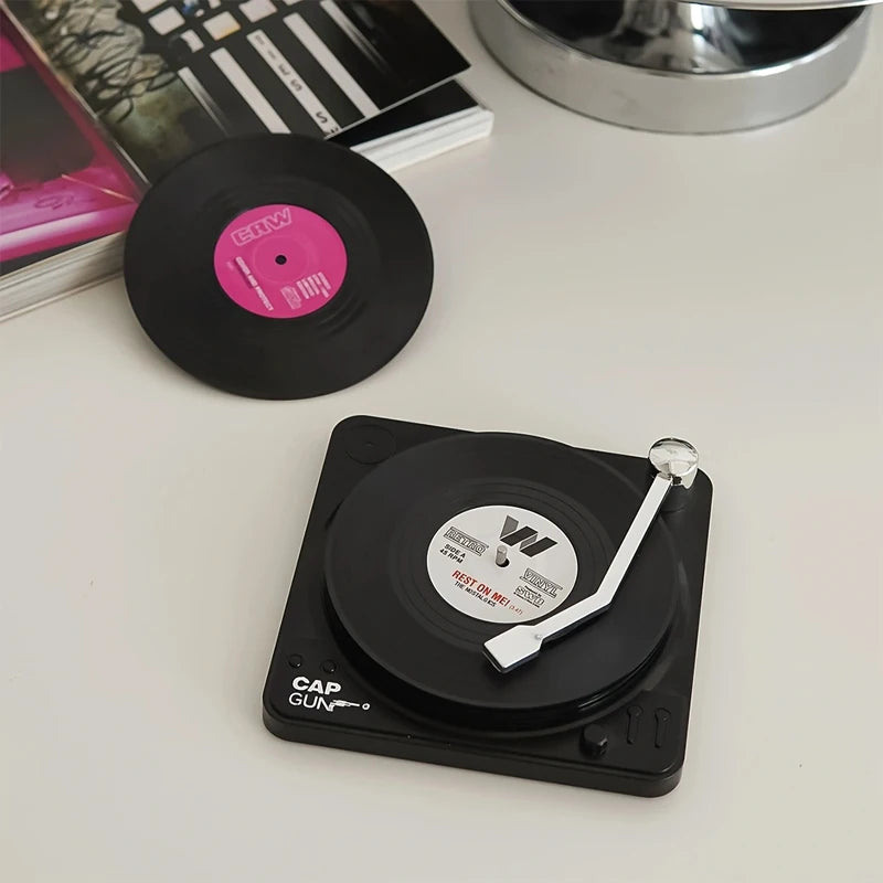 Miniature record player with a vinyl record coaster on a white surface