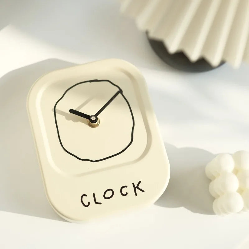 Small white clock with black hands on a light surface