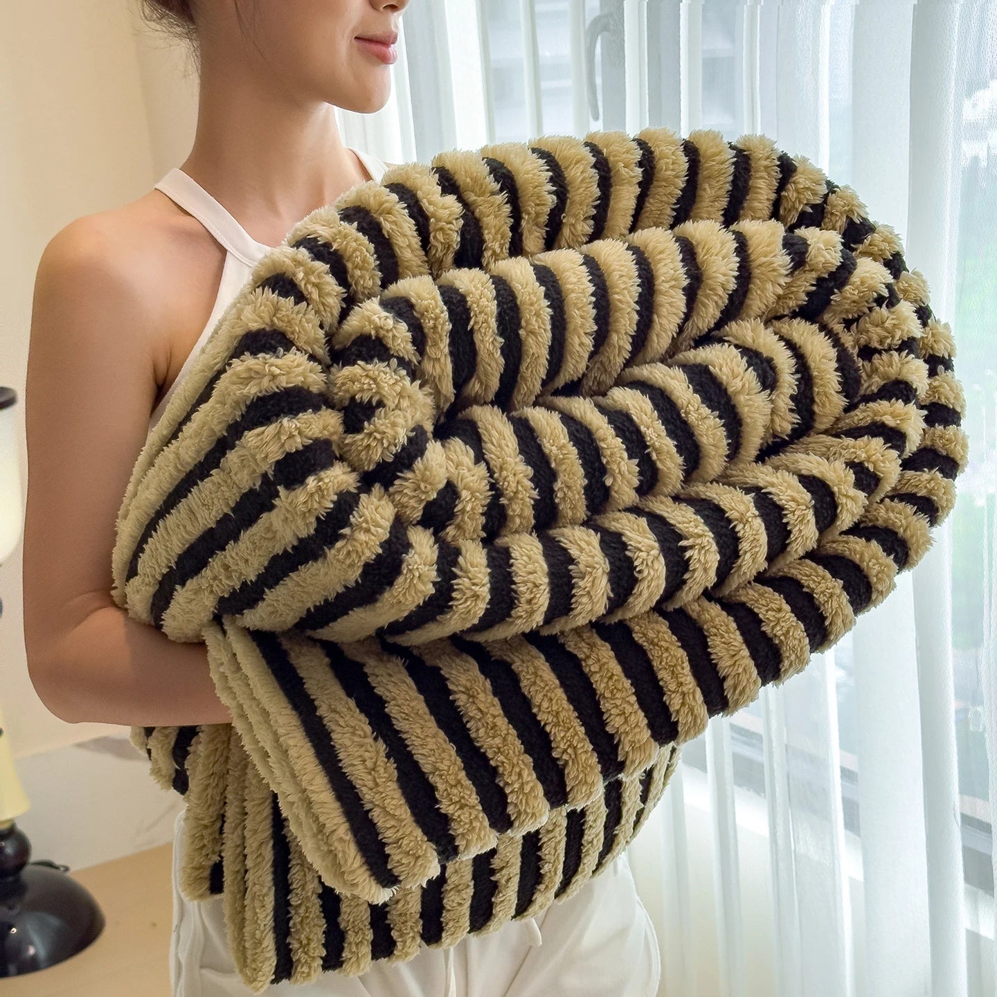 Person holding a striped blanket with a neutral background