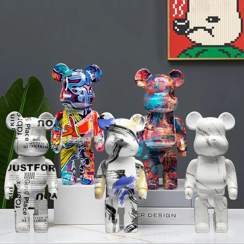 Five bear ornaments displayed together, featuring newspaper lettering, colourful graffiti, abstract brushstrokes, multicoloured paint effects and a white marble-effect design.