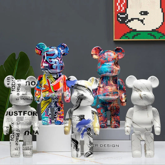 Five bear ornaments displayed together, featuring newspaper lettering, colourful graffiti, abstract brushstrokes, multicoloured paint effects and a white marble-effect design.