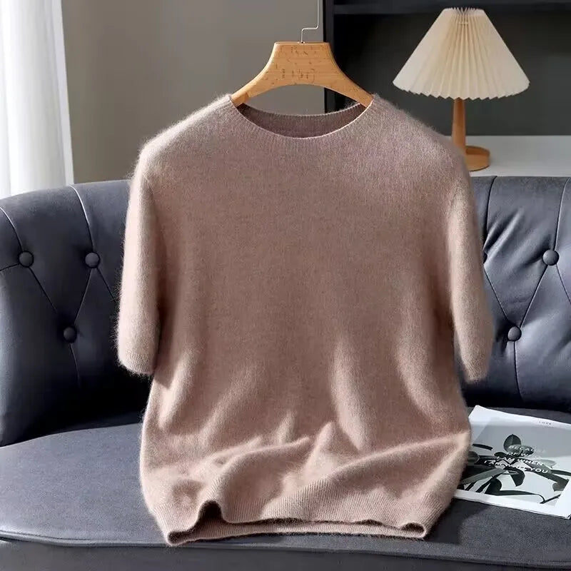 Beige sweater on a hanger against a gray sofa background