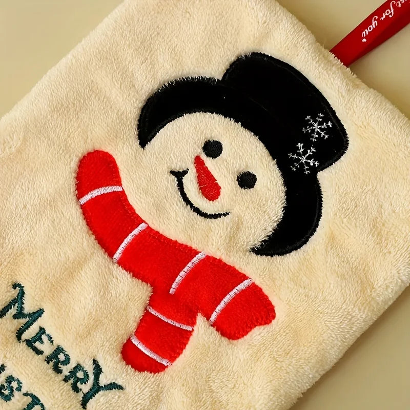 White hand towel with a snowman design wearing a red scarf and black hat, on a beige background.