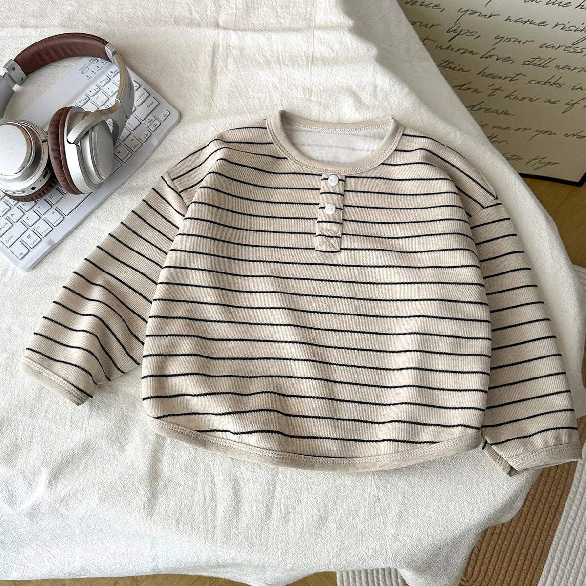 Striped sweater on a white surface with headphones and a keyboard in the background