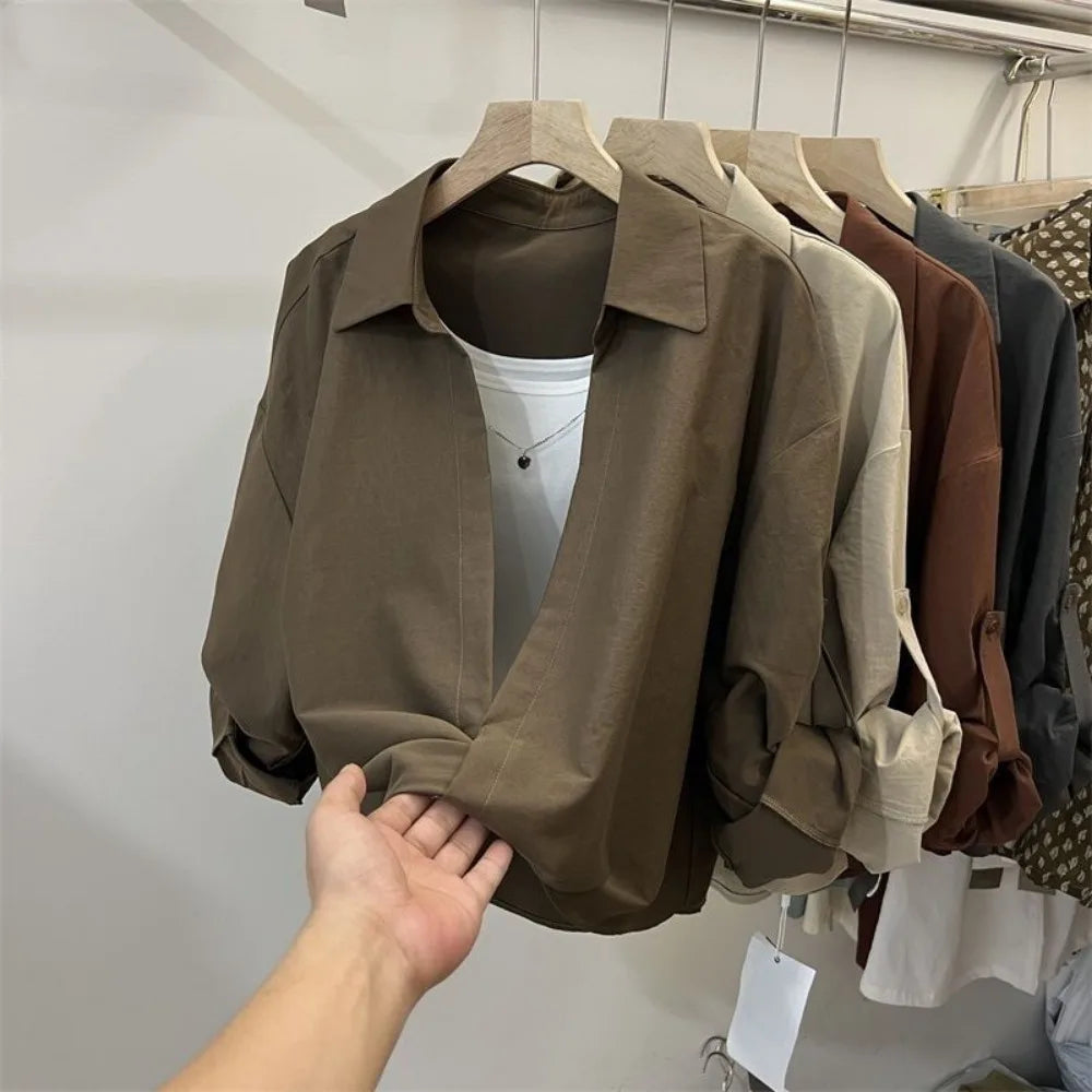 Women’s loose fit layered look blouse with long sleeves and collared neckline in neutral colours on a clothing rack