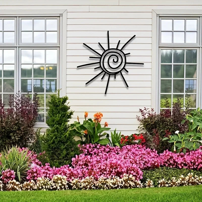 Decorative metal sun wall art on a house exterior with a garden in the foreground.