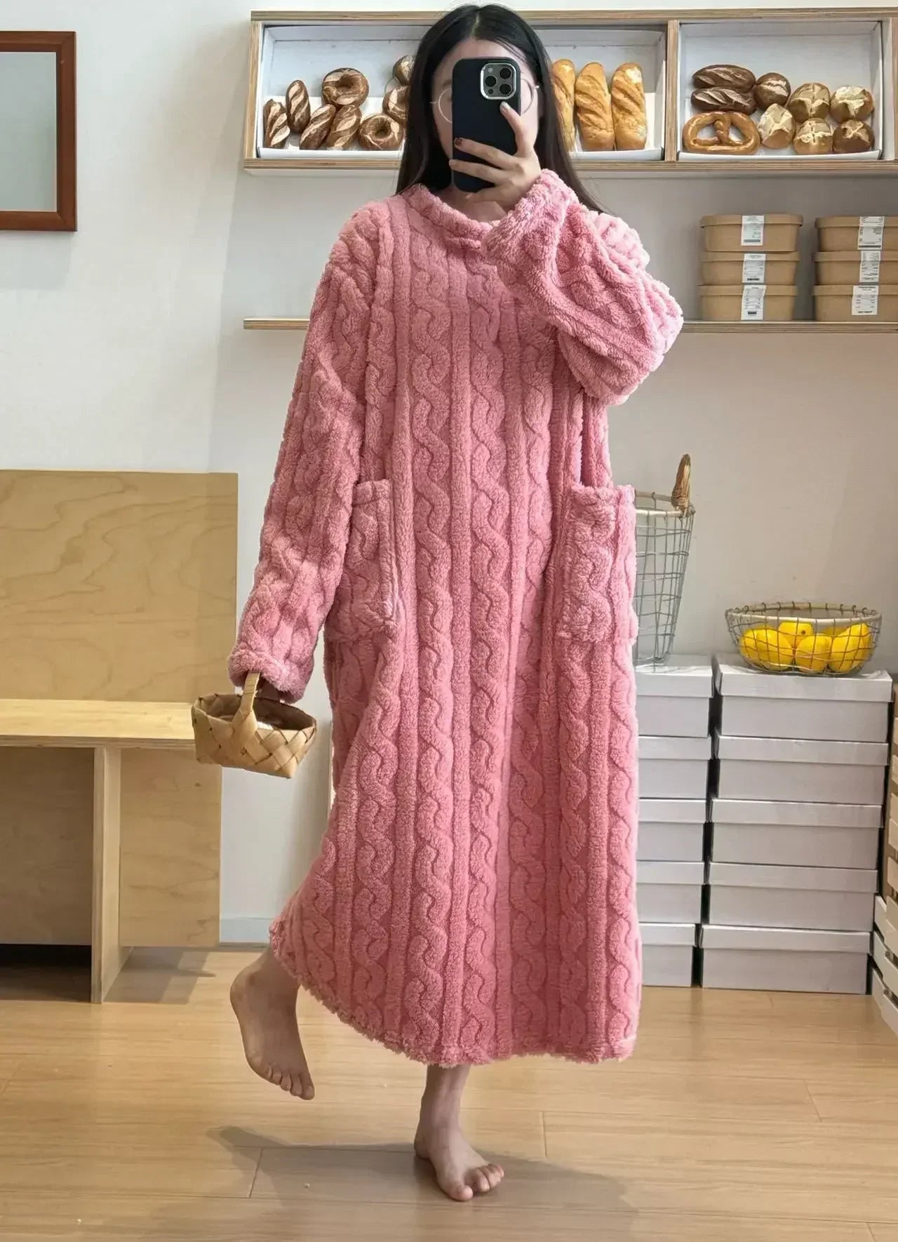 Person wearing a pink cable knit dress standing in a bakery.