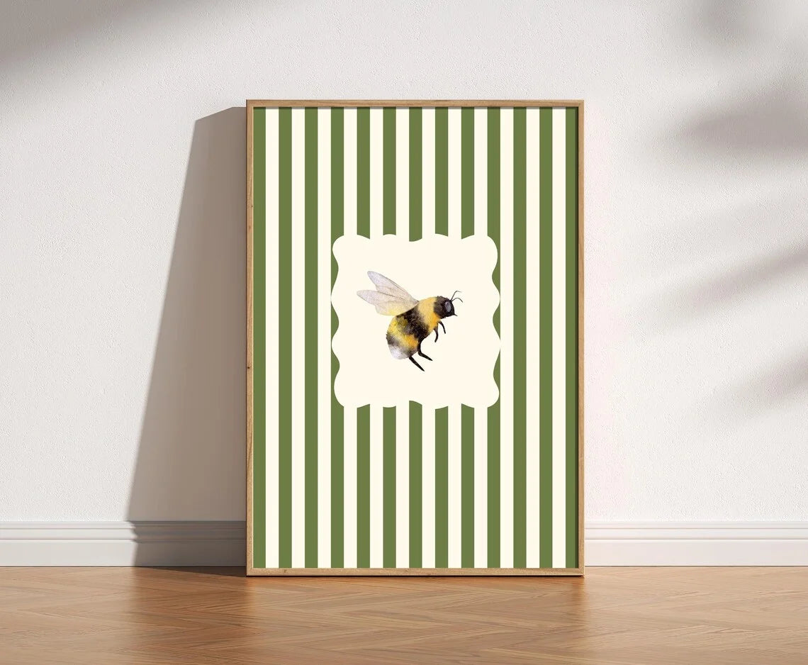 Framed artwork with a bee design on a green and white striped background
