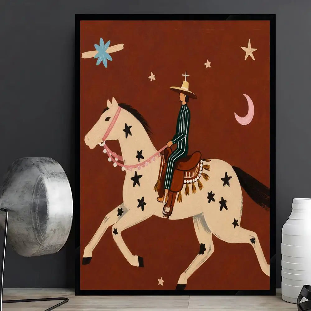 A framed art print featuring a stylized cowboy riding a spotted cream-colored horse against a dark reddish-brown background, displayed on a shelf next to a silver lamp and a white vase.