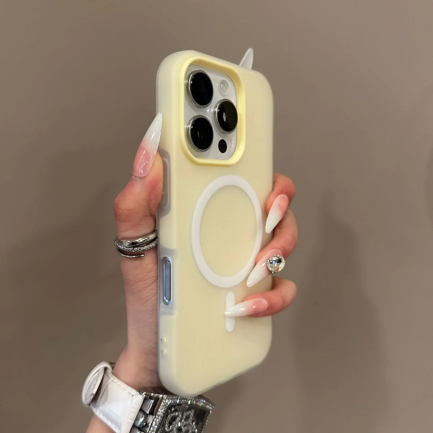 Hand holding a light yellow phone case with a brand logo against a brown background