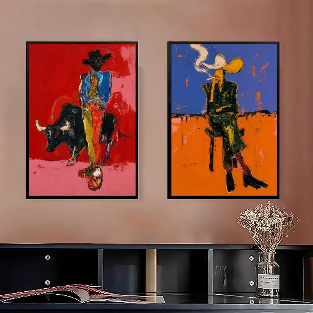 Two framed abstract cowboy paintings hanging side-by-side on a warm beige wall above a black shelf with a vase of dried flowers.
