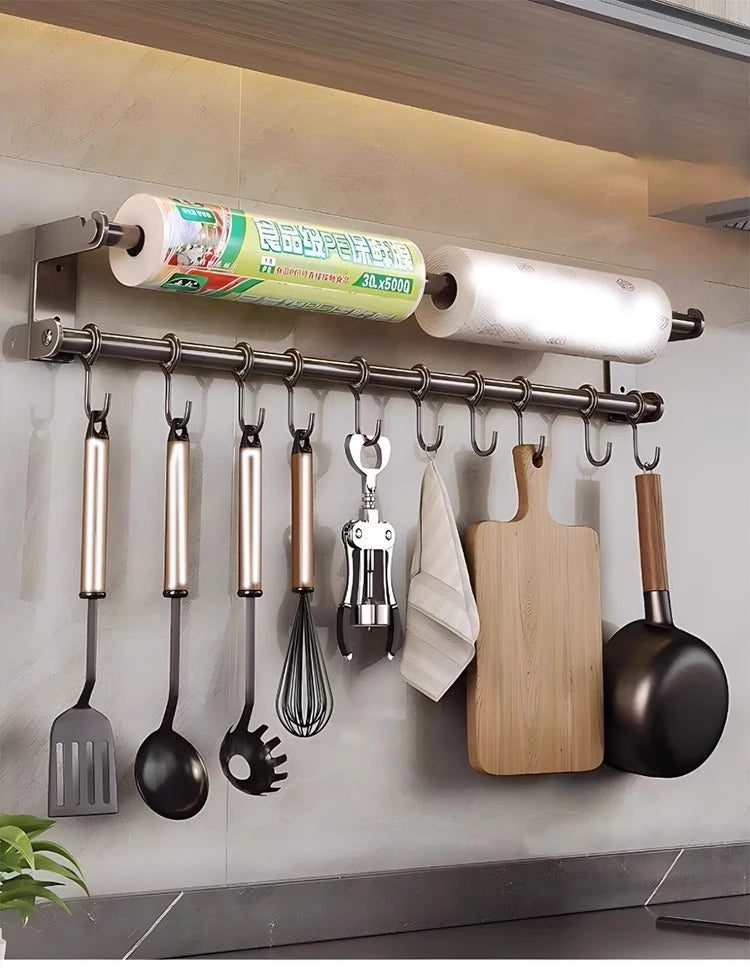Kitchen utensils and tools hanging on a wall-mounted rack with paper towels above.