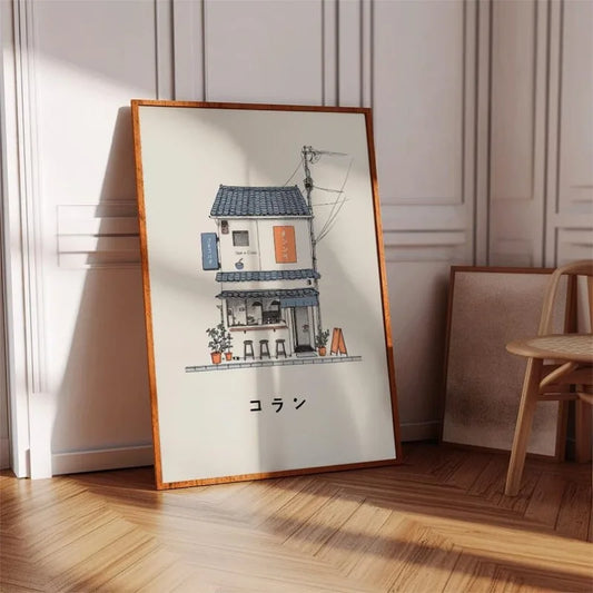 A framed art print featuring a detailed illustration of a Japanese house and storefront with the text 'シルバー' at the bottom, leaning against a paneled wall on a wooden floor next to a chair.