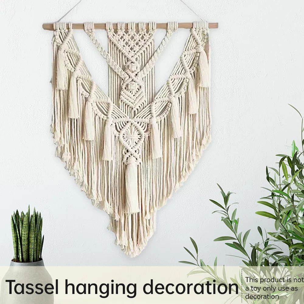 Tassel hanging decoration on a white wall with plants below.