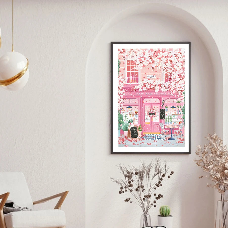 Framed artwork of a pink building with cherry blossoms in a room with a white wall and decorative elements.