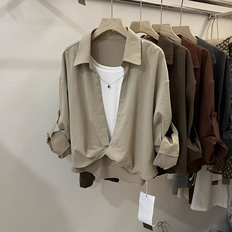 Women’s loose fit layered look blouse with long sleeves and collared neckline in neutral colours on a clothing rack