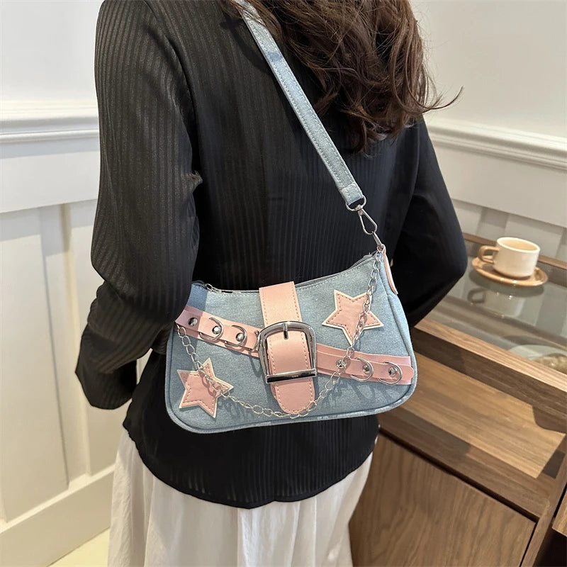 Person wearing a denim handbag with star and buckle details in an indoor setting.