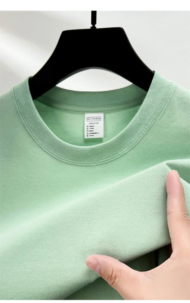 Light green sweatshirt on a hanger with a hand touching the fabric