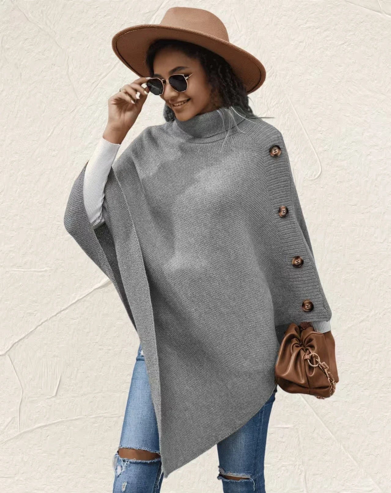 Women’s oversized grey poncho sweater with turtleneck and button sleeve detail styled with jeans