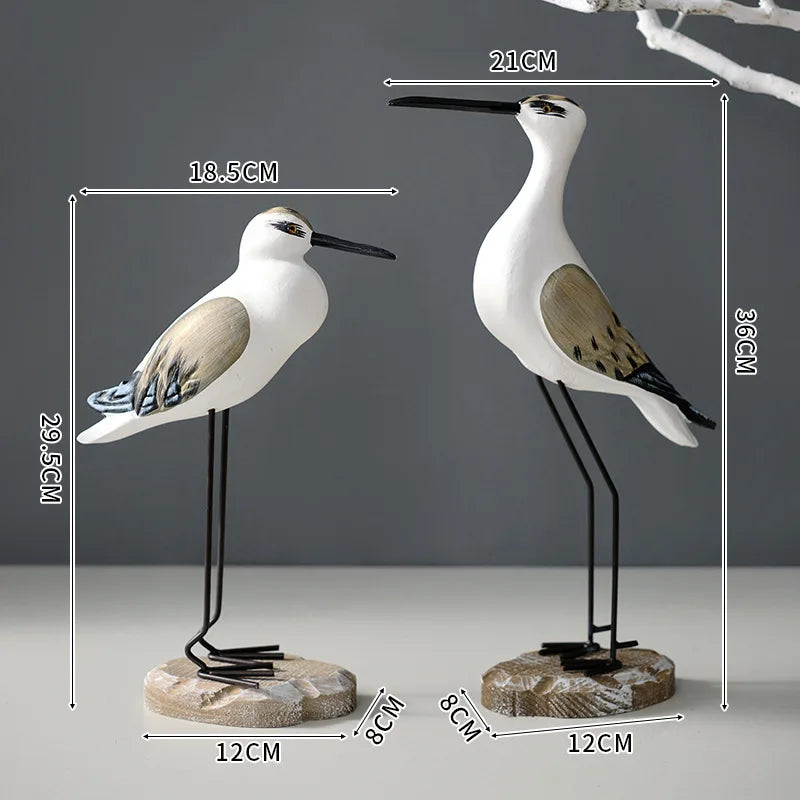 Two bird figurines with measurements on a gray background