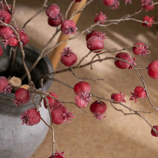 Dried branches with red berries in a pot on a wooden surface