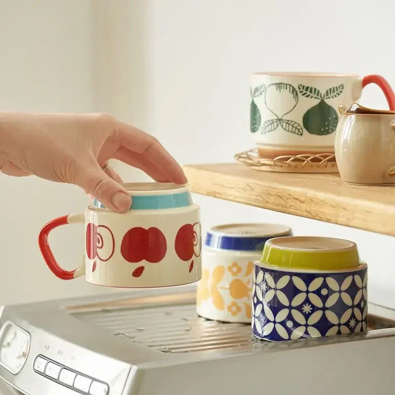 Colorful mugs on a kitchen counter with a hand reaching for one mug.