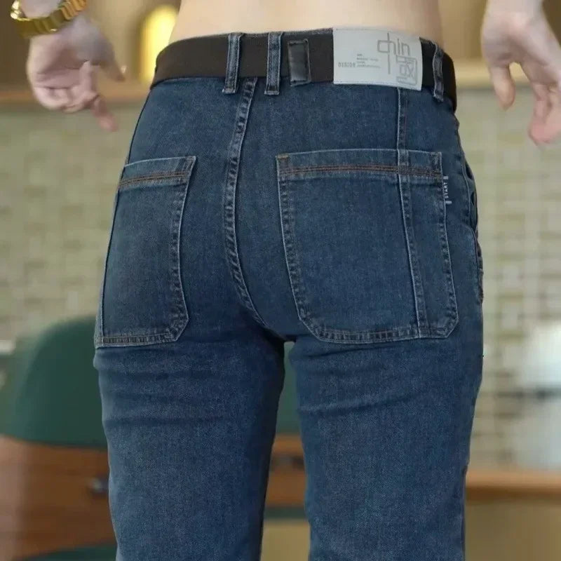 Person wearing blue jeans with a visible brand label on a blurred indoor background