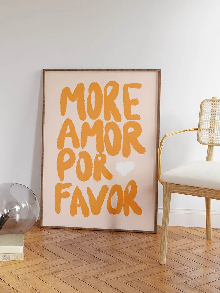 Framed artwork with 'More Amor Por Favor' text in a room with a chair and decor items.