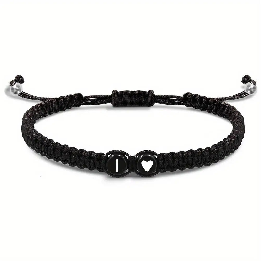 Black braided bracelet with heart and circle charm on a white background