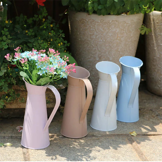Set of four colorful metal vases with flowers on a stone surface