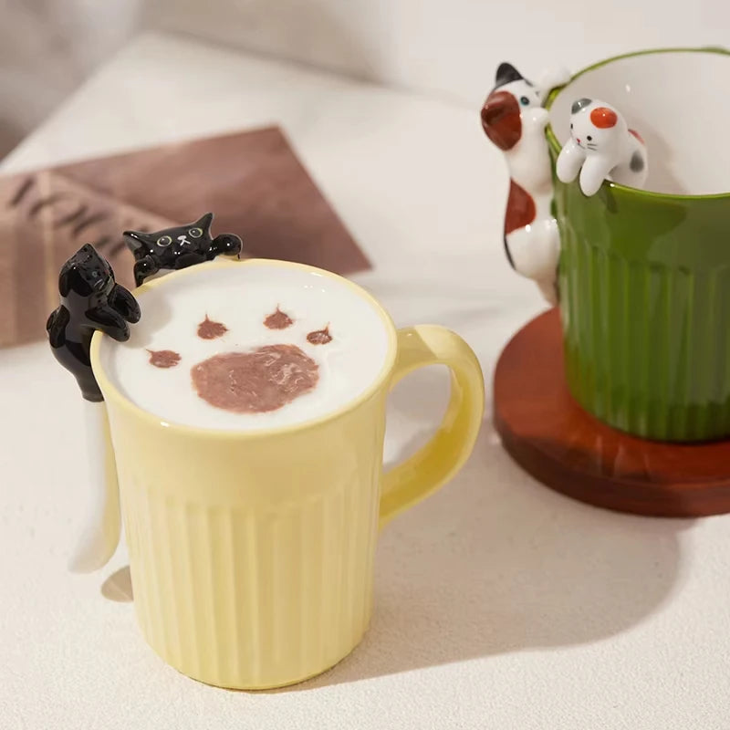 Green and yellow ceramic cat mugs with a 3D cat climbing over the rim.