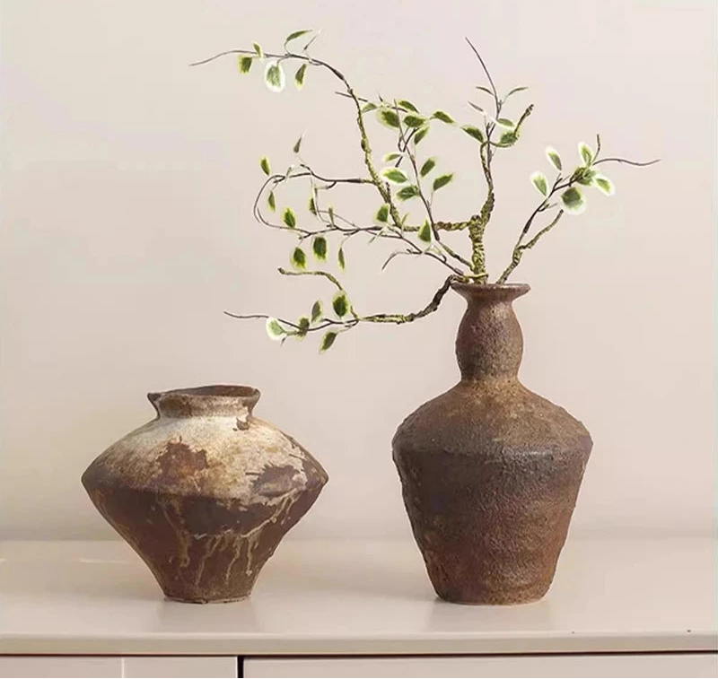 Wabi-sabi ceramic vase with rustic textured brown finish, styled with delicate green branches for natural home decor.