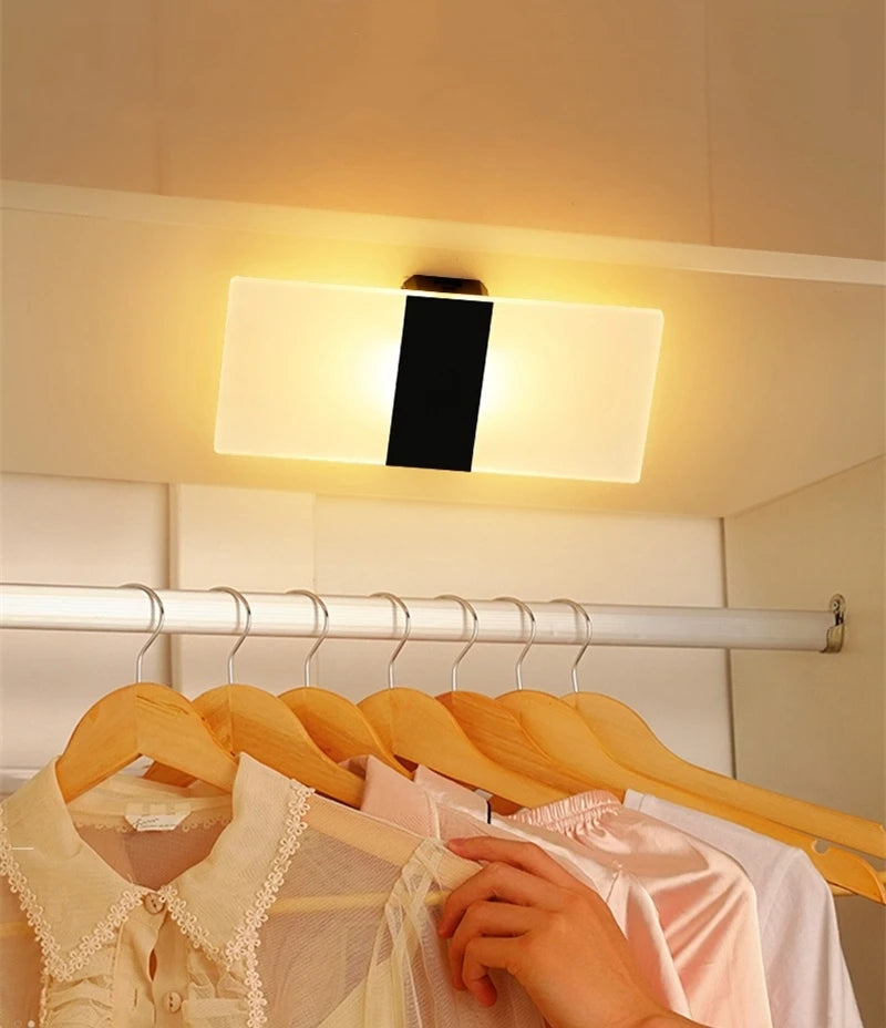 Clothing rack with shirts and a hand reaching out, illuminated by a ceiling light.