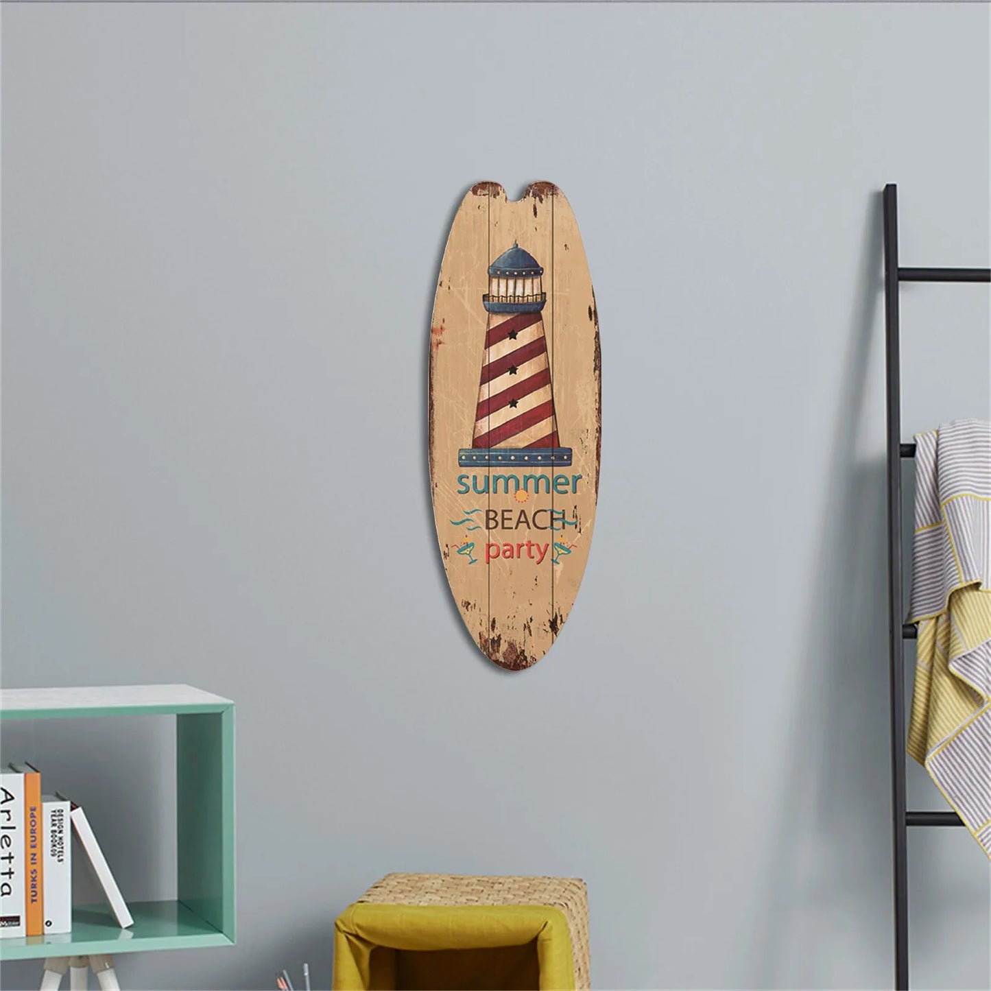 Decorative surfboard with lighthouse design and 'summer beach party' text on a gray wall.
