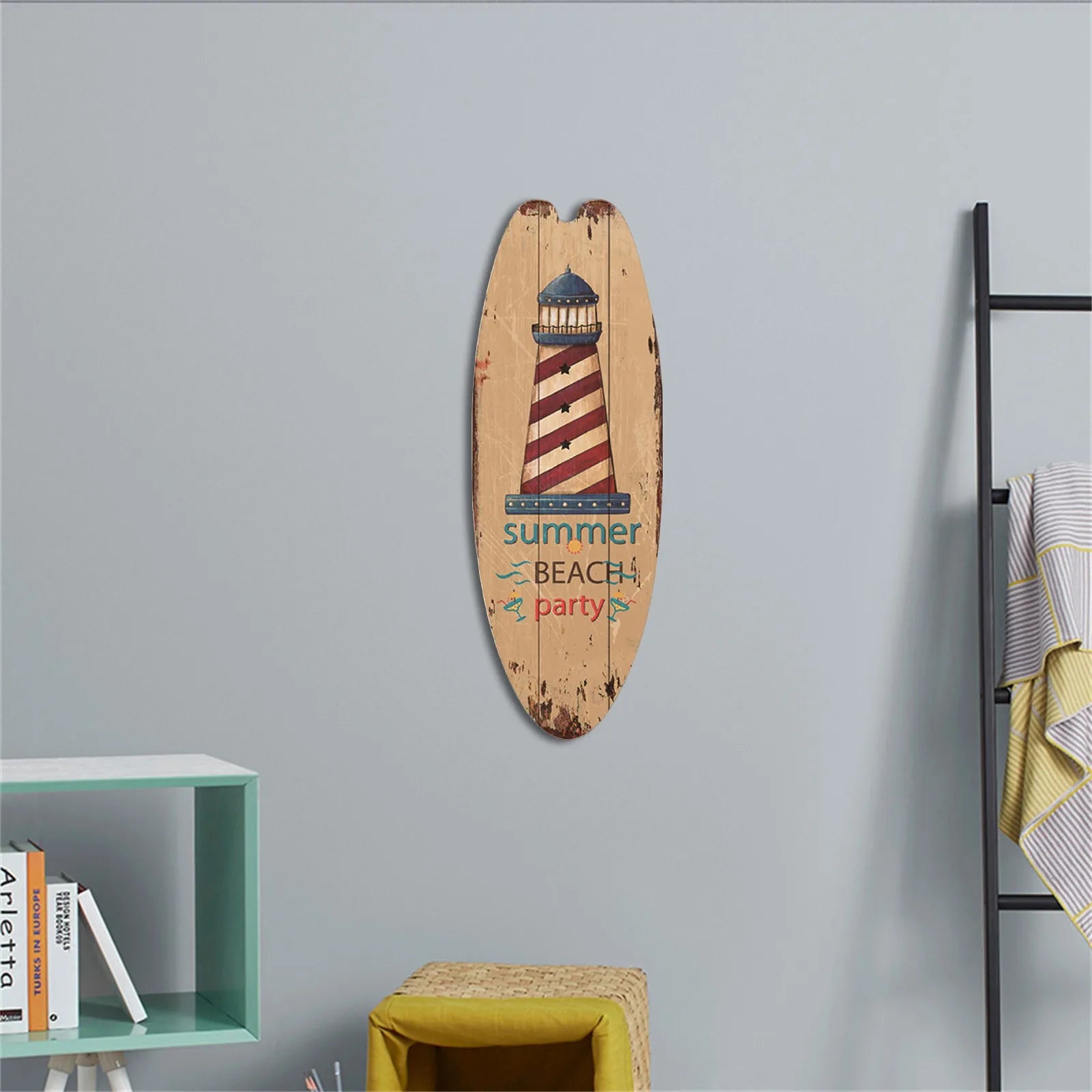 Decorative surfboard with lighthouse design and 'summer beach party' text on a gray wall.