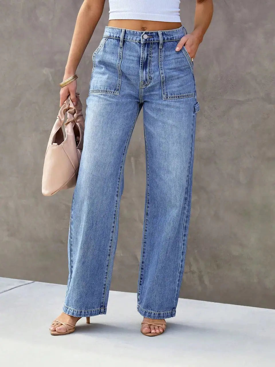 Person wearing high-waisted blue jeans with a neutral background