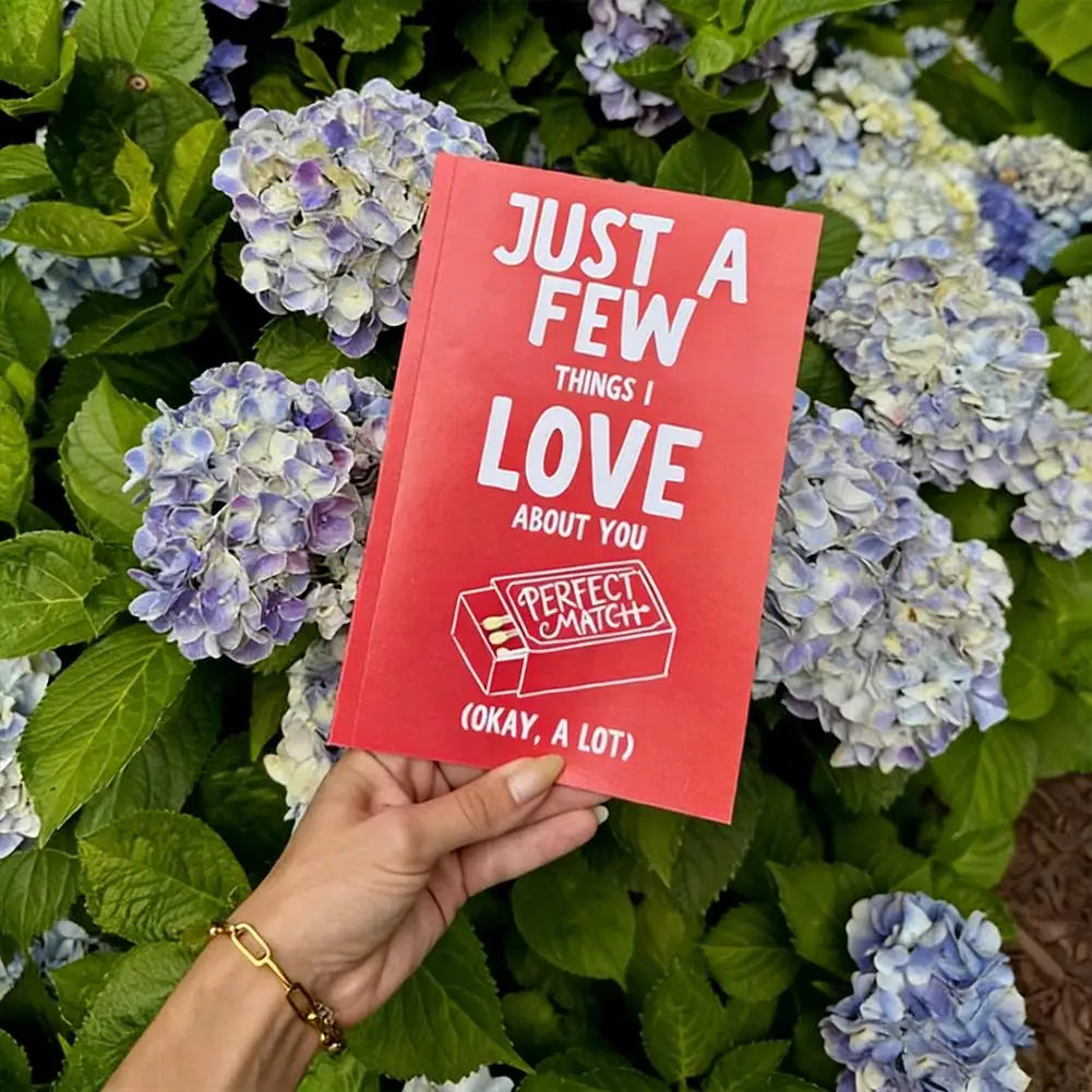 Red book titled 'Just a Few Things I Love About You' held in front of hydrangea flowers