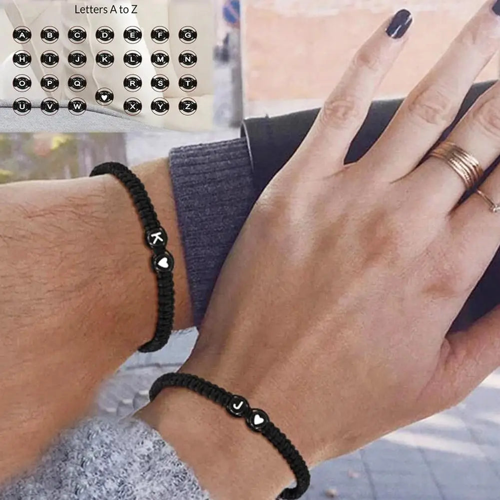 Black beaded bracelet on wrist with close-up of hand and additional bracelet, inset showing letter 'K'.